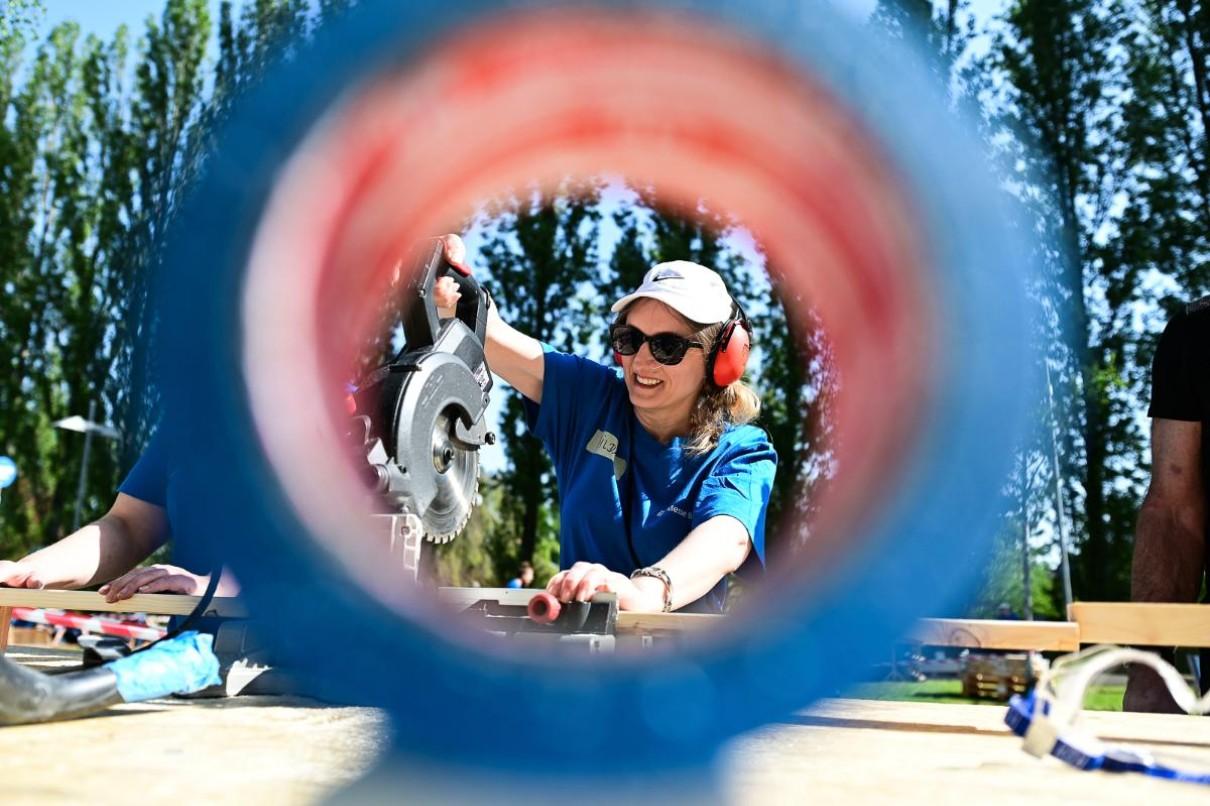 Auf dem Bild ist eine Frau an einer Kreissäge zu sehen, die durch ein Rohr fotografiert wird.
